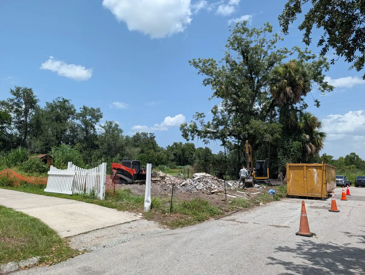 Excavator and roll-off dumpster clearing a Polk County property