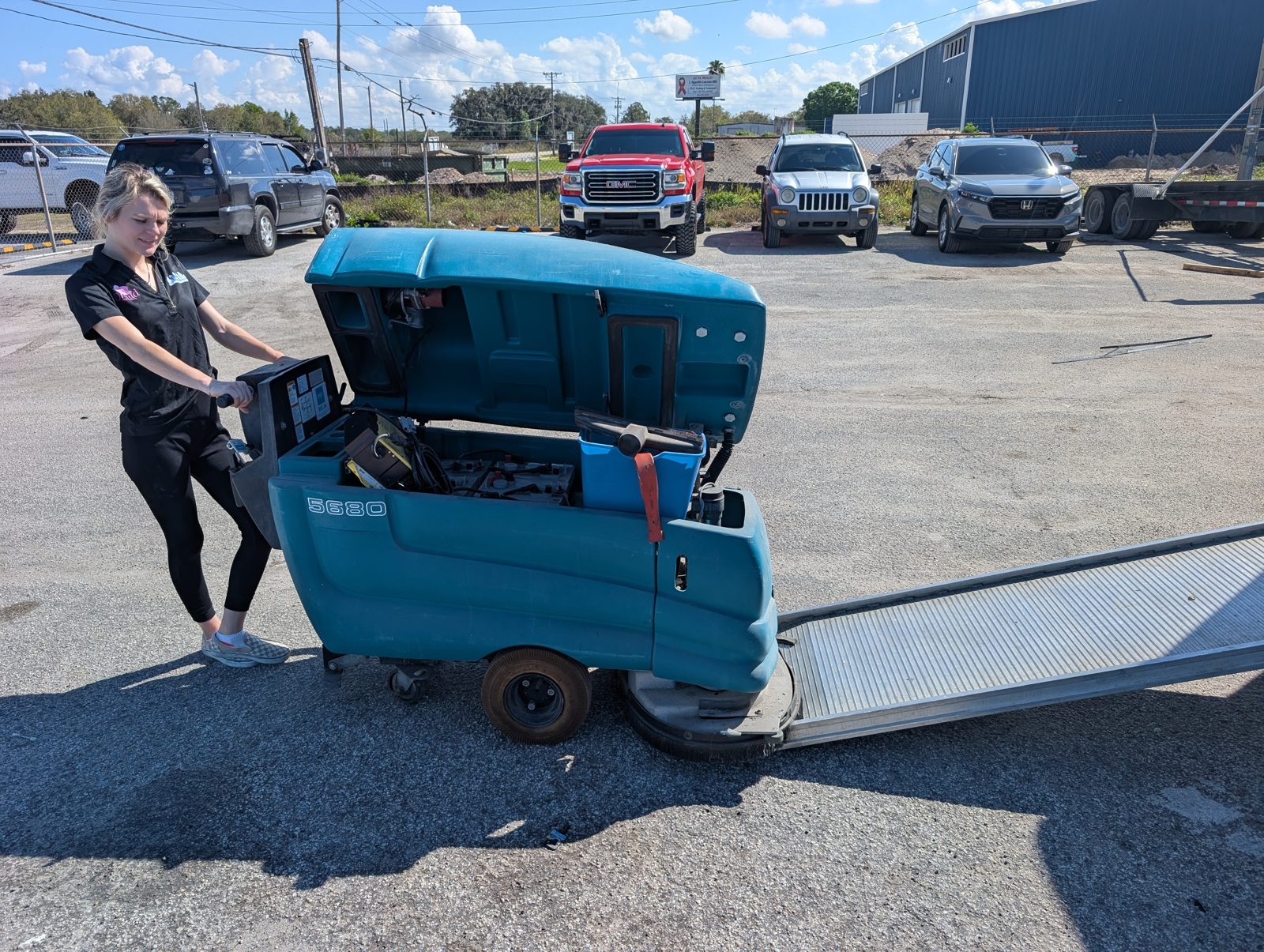 Orchid Cleaning crew member operating a Tennant ride-on floor scrubber