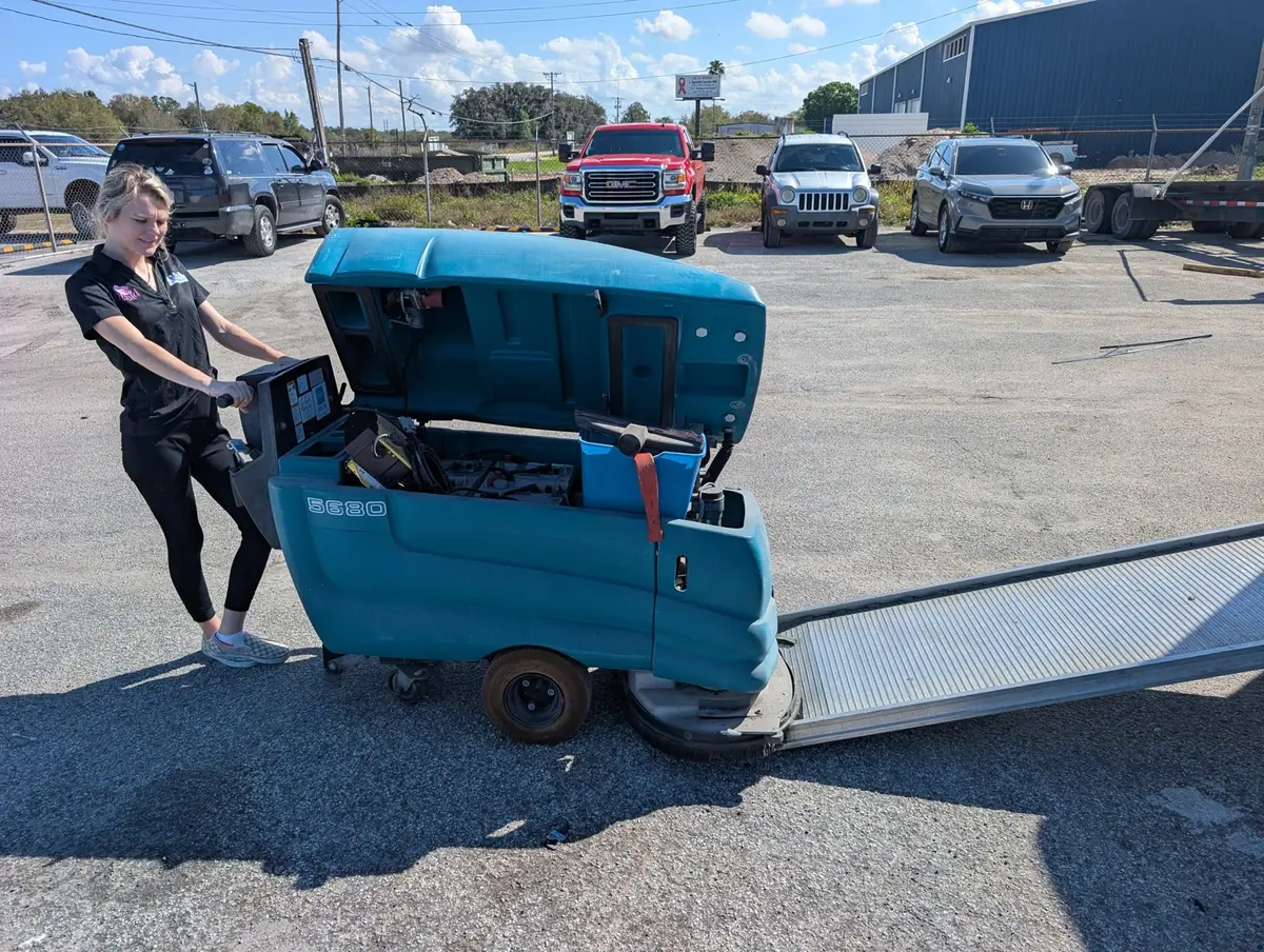 Orchid Cleaning crew member operating a Tennant ride-on floor scrubber