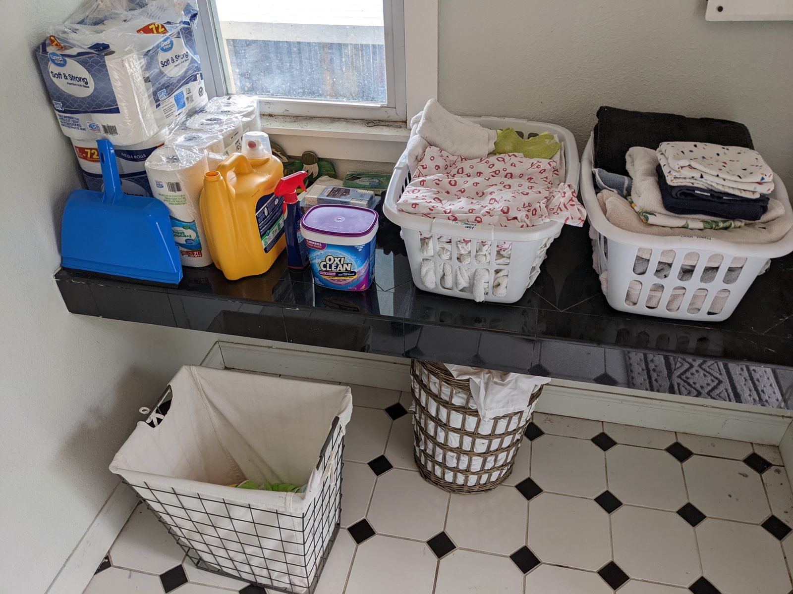Folded towels and linens in laundry baskets with cleaning supplies, ready for a turnover