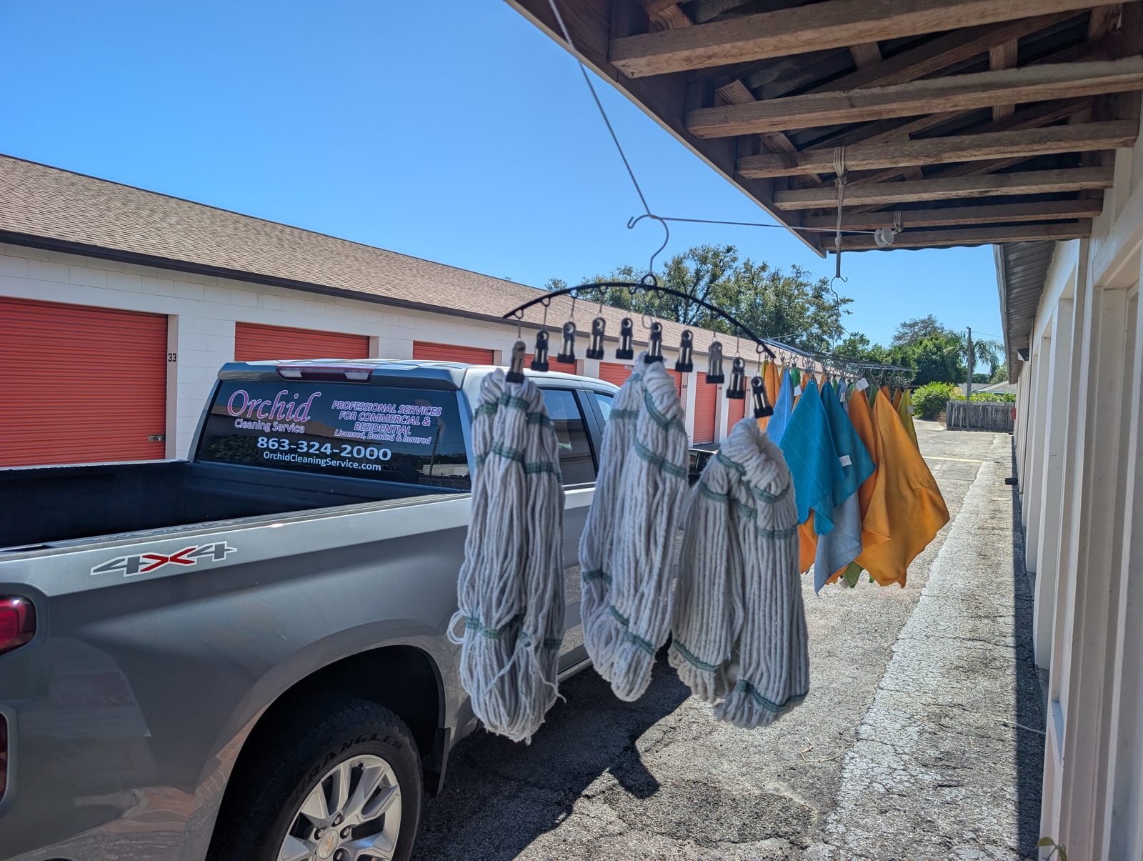Mop heads and microfiber cloths hung out to dry beside an Orchid Cleaning Service truck