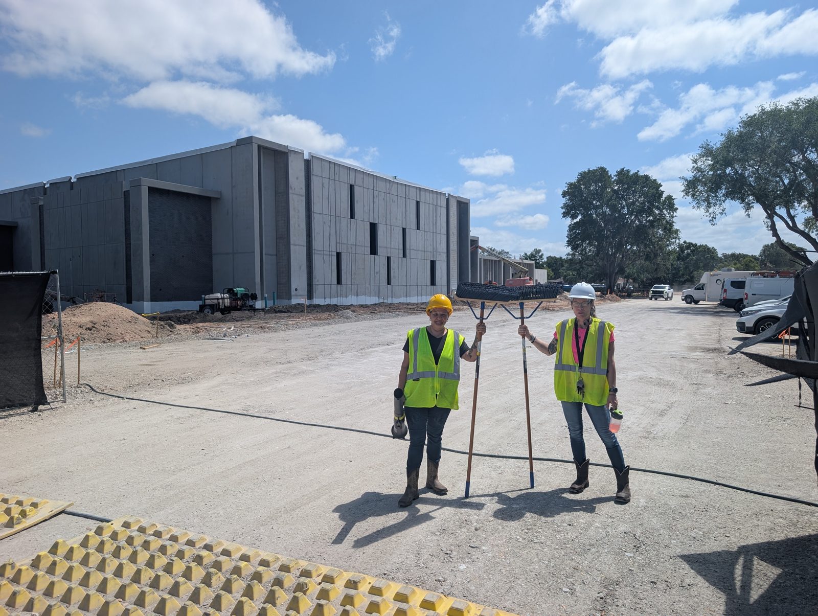 Two Orchid Cleaning crew members in hard hats and safety vests with push brooms outside the Winter Haven Recreation and Cultural Center
